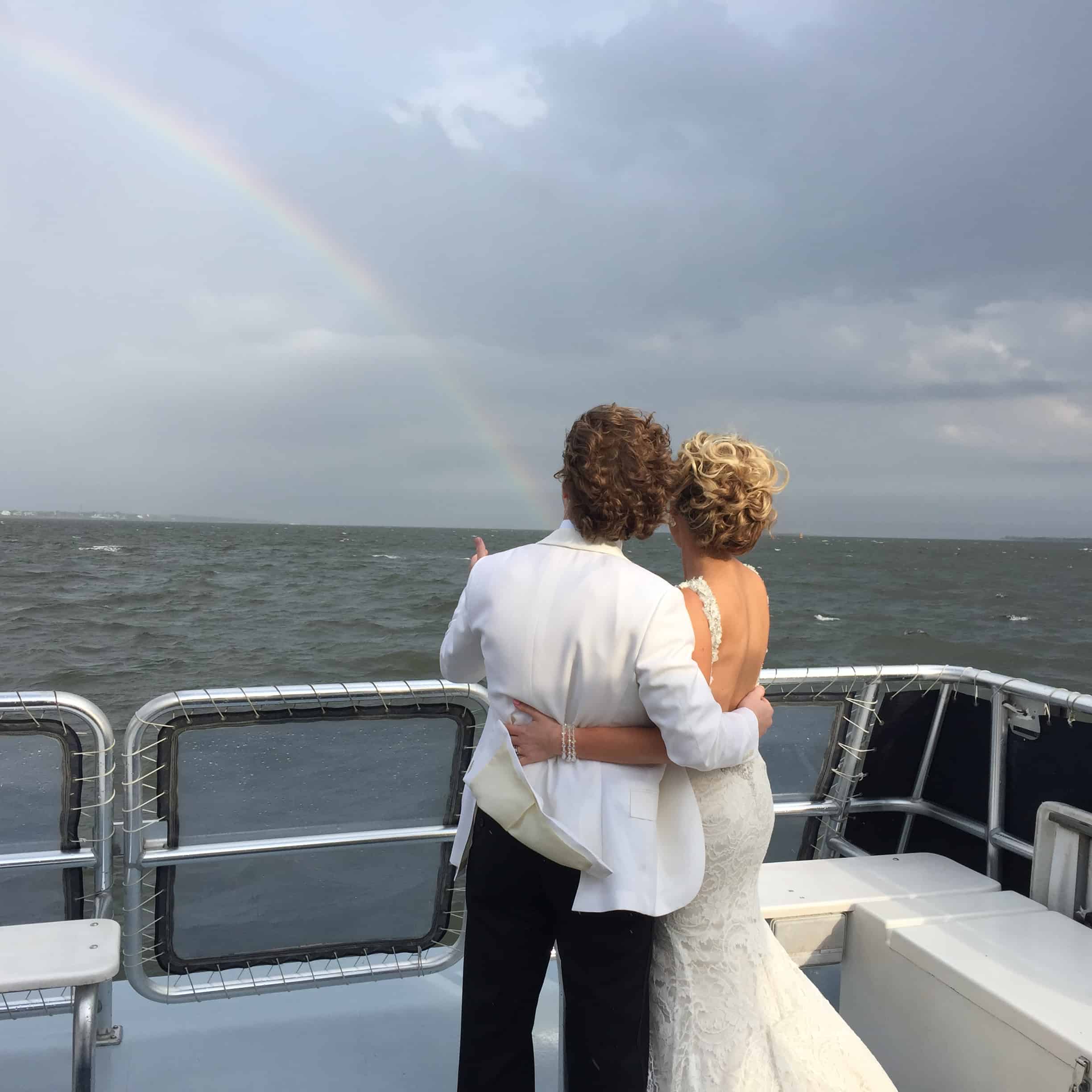 Rainbow appears on the water as Wedding couple admire it from the boat. Private charter boat Charleston, SC