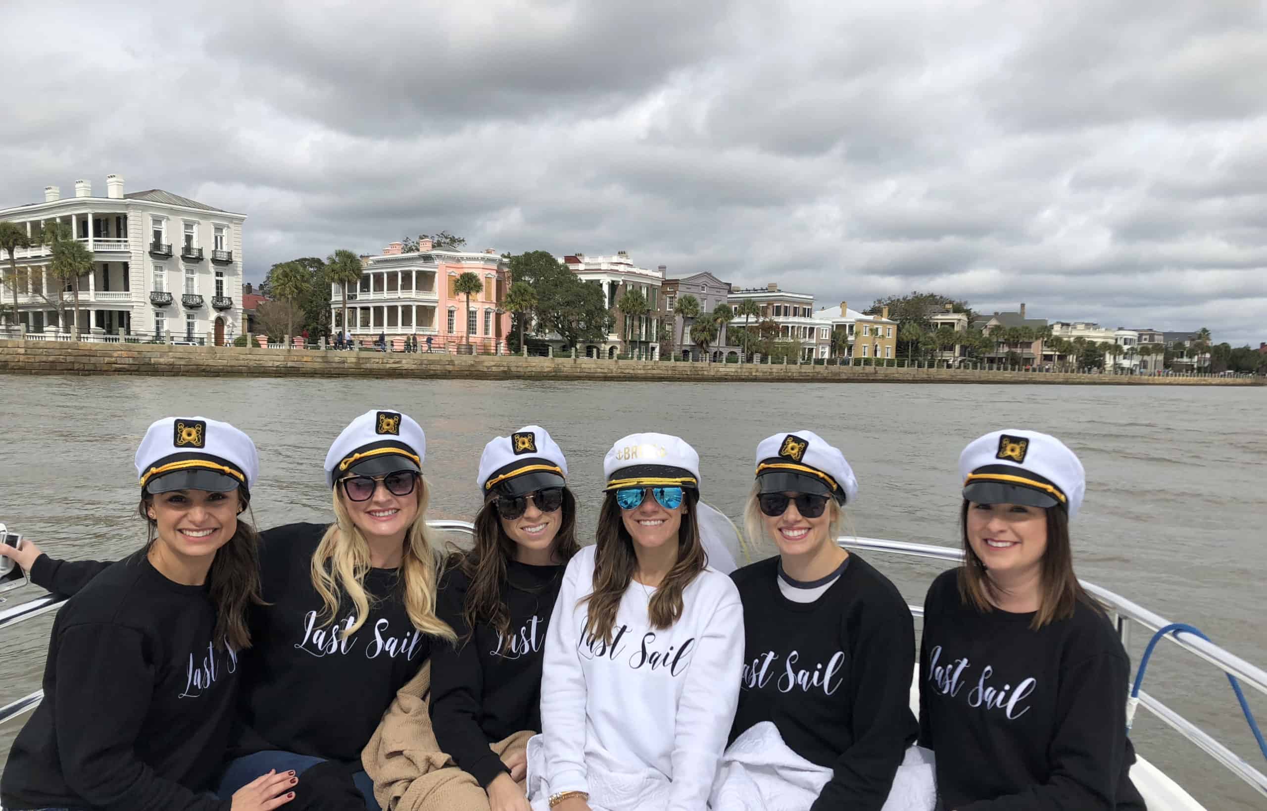 Bachelorette party pictured on the boat in front of The Battery with sailor hats and "Last Sail" sweaters on. Private charter Charleston, SC